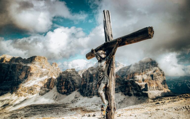 Wooden crucifix against a dramatic mountain backdrop with clouds.