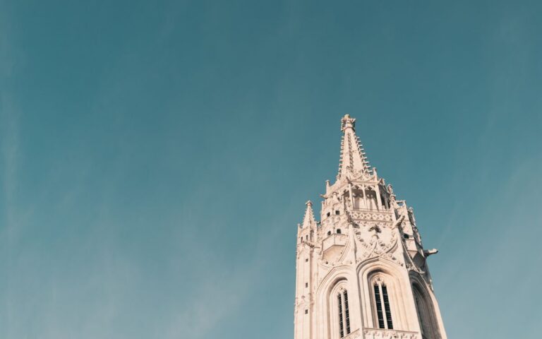 A low angle shot of the Matthias Church tower in Budapest against a clear blue sky.