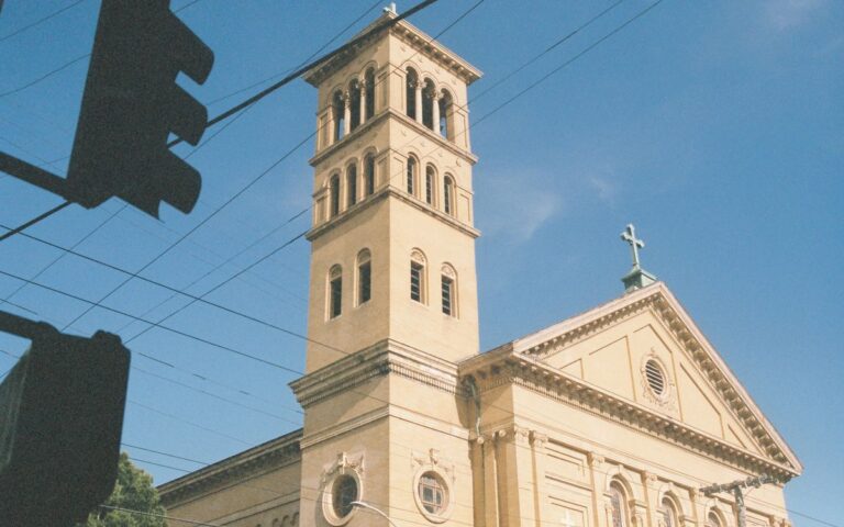 A beautiful church tower with Romanesque architecture style set against a clear blue sky.