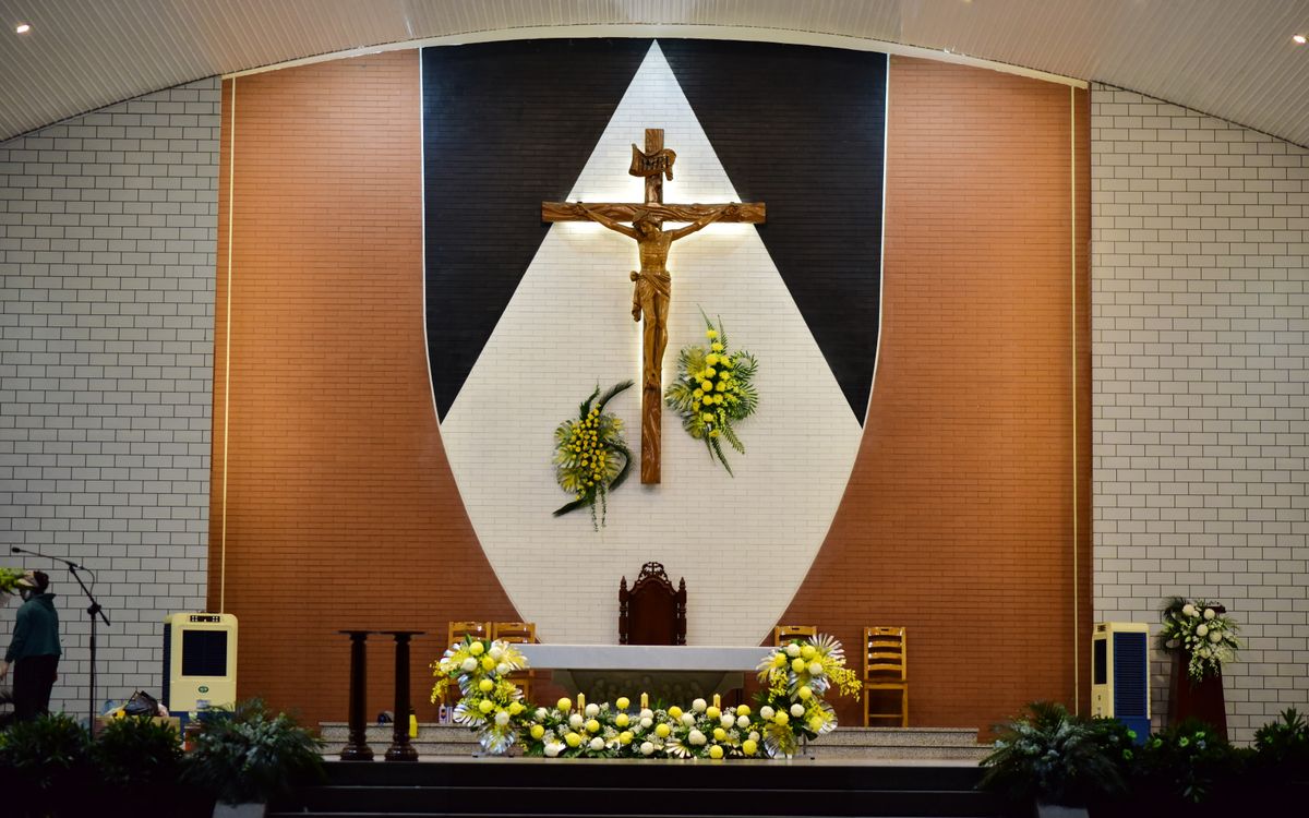 A church altar featuring a prominent crucifix and floral decorations, creating a serene spiritual atmosphere.