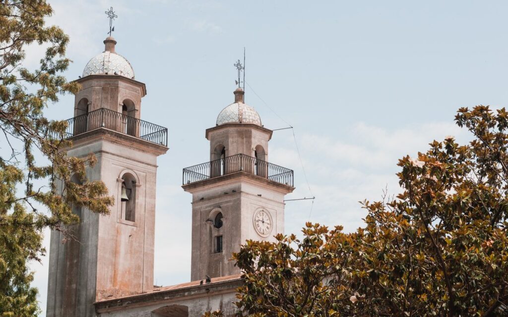 Two historic church towers rise above lush greenery in Colonia del Sacramento, Uruguay.