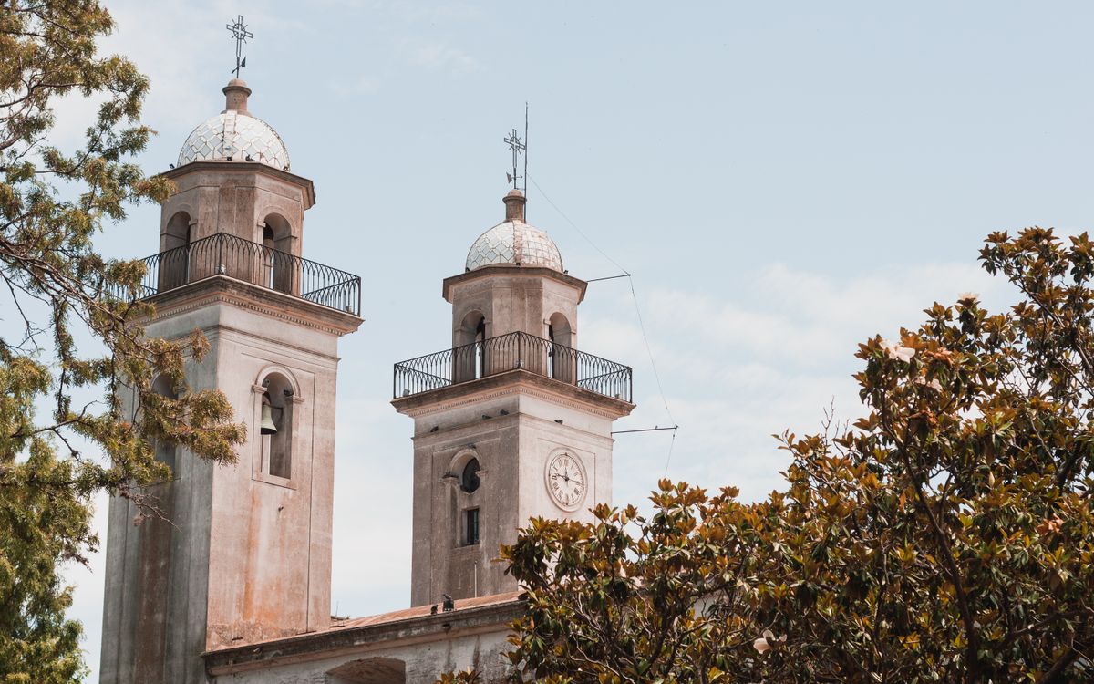 Two historic church towers rise above lush greenery in Colonia del Sacramento, Uruguay.