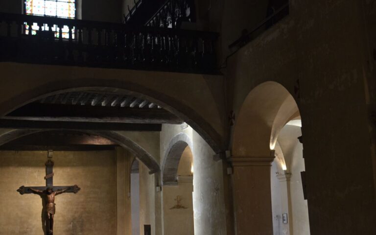 A serene view of a historic church interior featuring a crucifix and architectural arches.