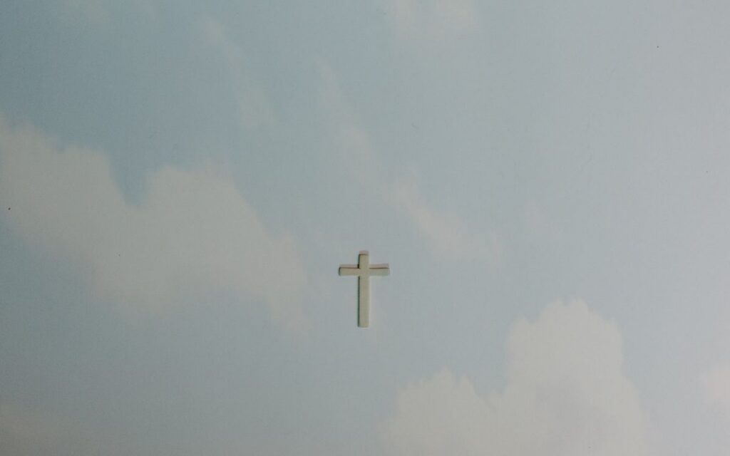 A solitary cross set against a softly clouded sky, symbolizing peace and spirituality.