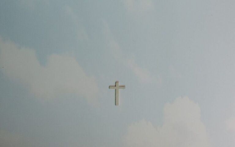 A solitary cross set against a softly clouded sky, symbolizing peace and spirituality.