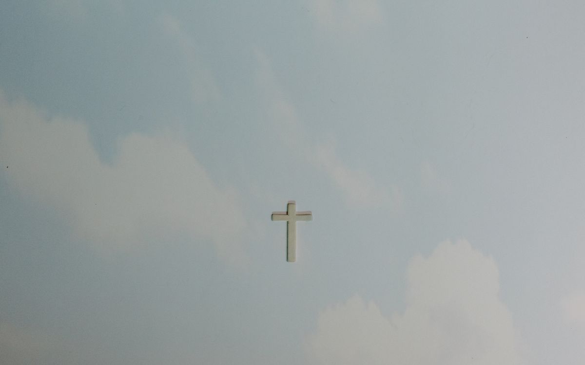 A solitary cross set against a softly clouded sky, symbolizing peace and spirituality.
