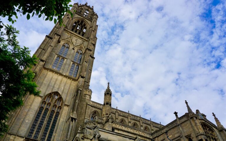 Low angle view of St Botolph's Church tower in Boston, England, under a cloudy blue sky.