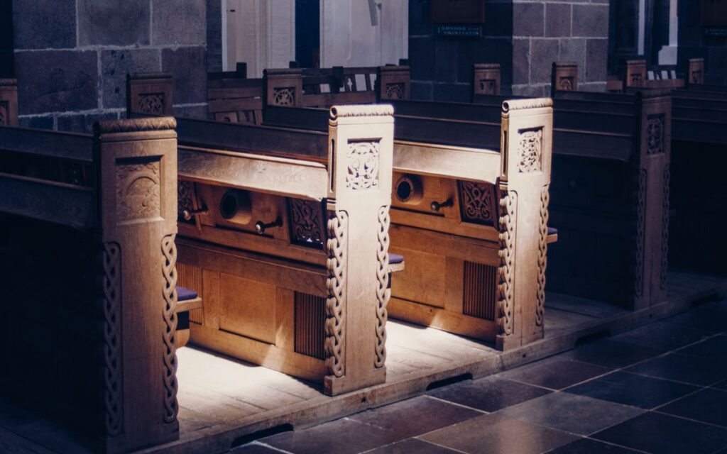 Beautifully carved wooden pews inside a dimly lit church, highlighting architectural elegance.