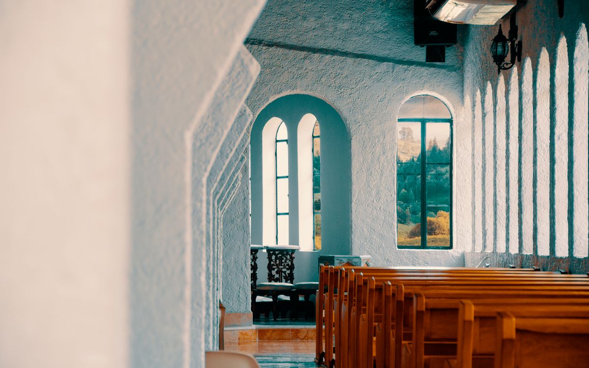 Peaceful church interior in Montería with rows of wooden benches and sunlight streaming through windows.