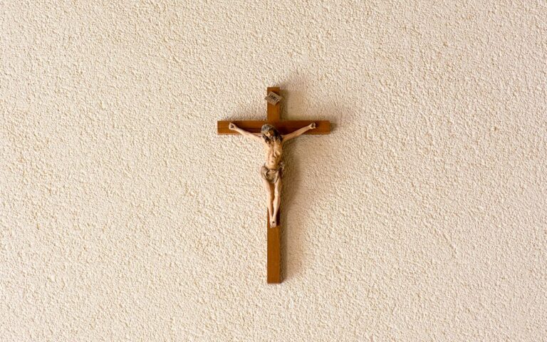 A detailed wooden crucifix depicting Jesus Christ on a textured wall, symbolizing Christian faith.