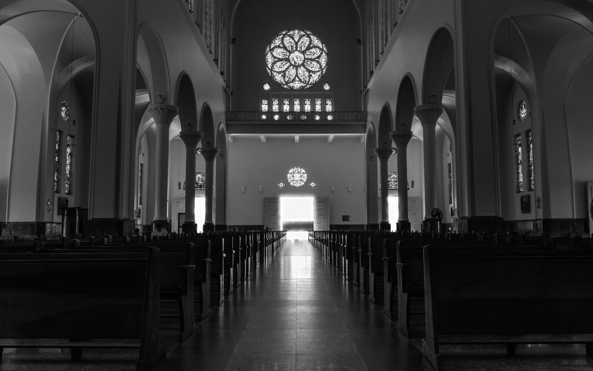 A timeless black and white photo showcasing the serene interior of a church with arches and stained glass windows.