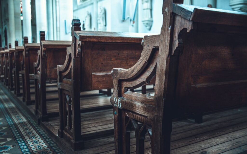 A serene view of traditional wooden church pews aligned in a sunlit interior.