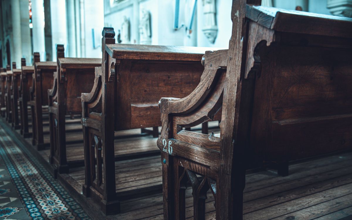 A serene view of traditional wooden church pews aligned in a sunlit interior.