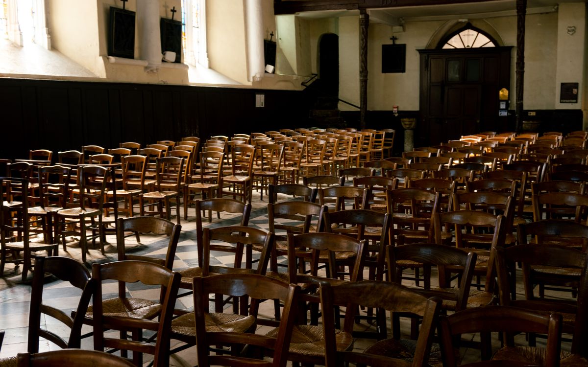 A serene church interior in France featuring rows of wooden chairs illuminated by warm sunlight through the windows.