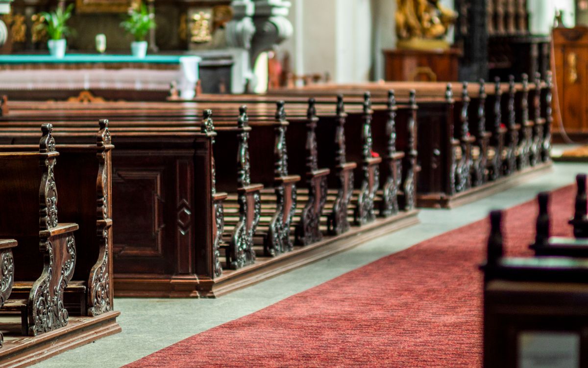 Detailed view of ornate wooden pews in an empty church interior, showcasing classical design.