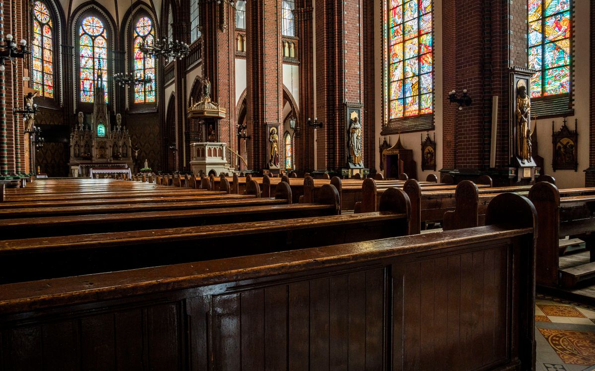 Empty church interior with stained glass and wooden pews.