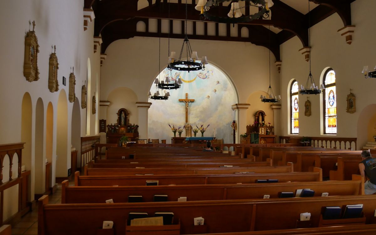 Atmospheric interior of a traditional church with wooden pews and stained glass windows.