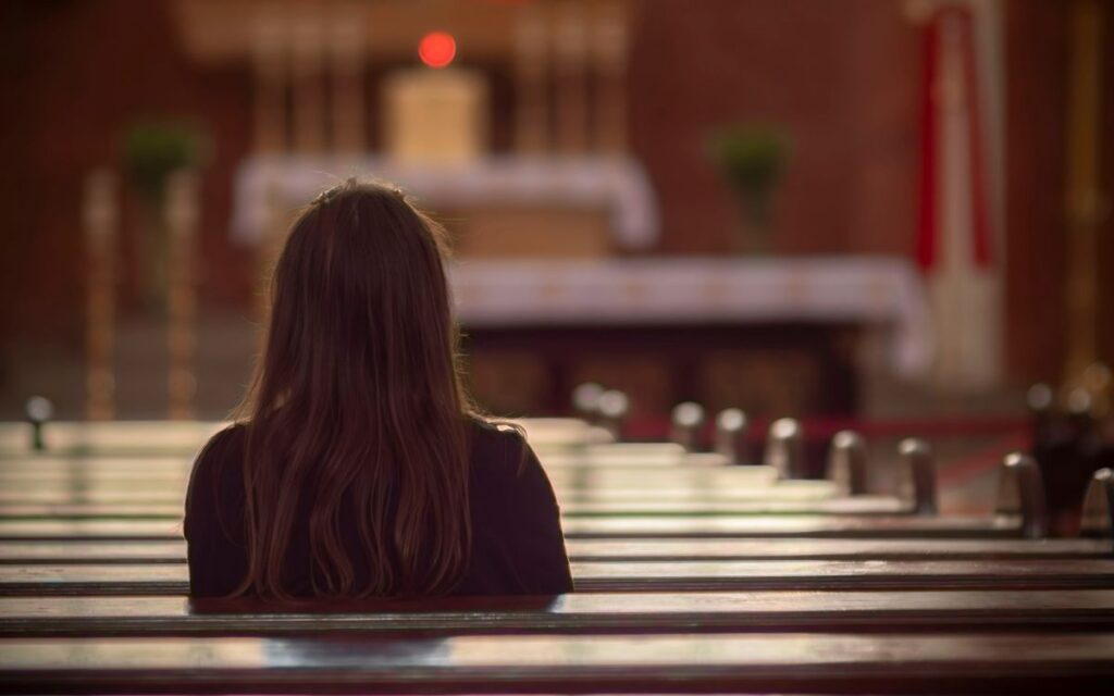 A woman sits in quiet reflection inside a beautiful church in Poland.