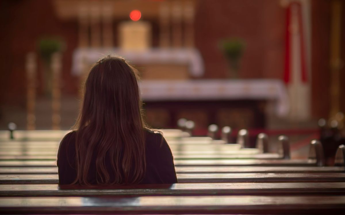 A woman sits in quiet reflection inside a beautiful church in Poland.