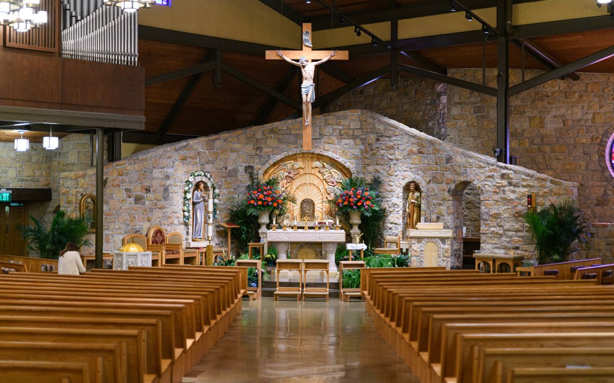 Beautiful church interior showcasing wooden pews and a detailed altar with religious statues.