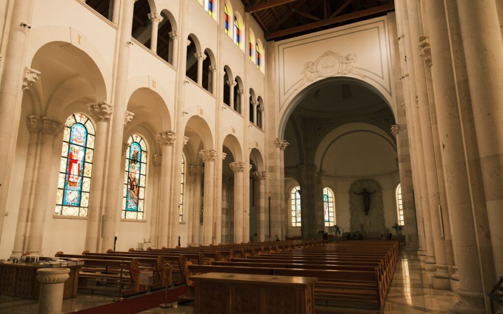 Capture of the beautiful interior of a cathedral in Priştine with stained glass windows and arches.