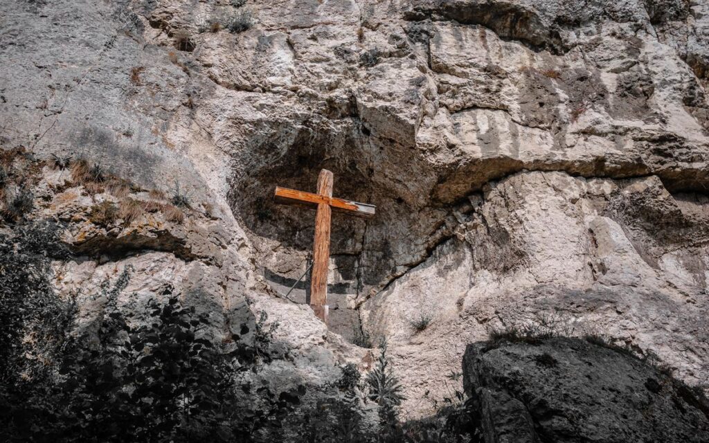 A wooden cross erected on a rugged rocky cliff, symbolizing faith amidst natural beauty in Efringen-Kirchen, Germany.