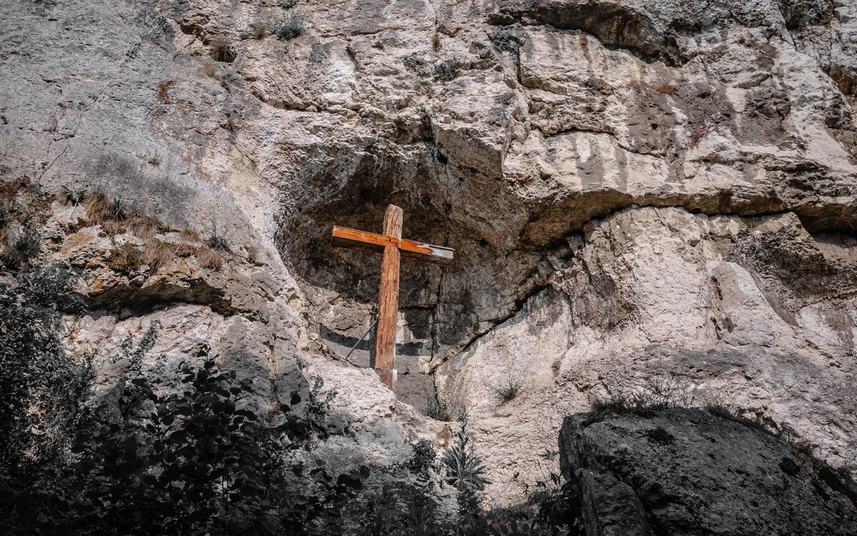 A wooden cross erected on a rugged rocky cliff, symbolizing faith amidst natural beauty in Efringen-Kirchen, Germany.