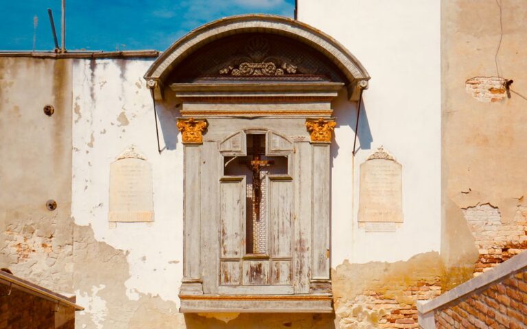 A rustic wall featuring religious symbols, weathered textures, and historical architecture details.