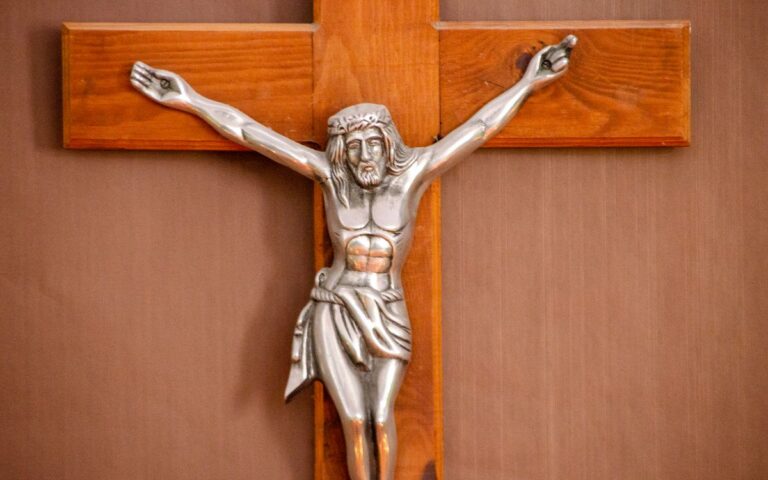 Close-up of a silver crucifix mounted on a wooden cross, highlighting Jesus Christ.