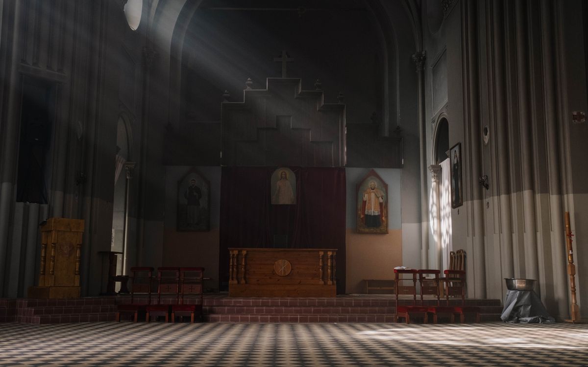 A serene church interior illuminated by sunlight, featuring an altar and religious art.