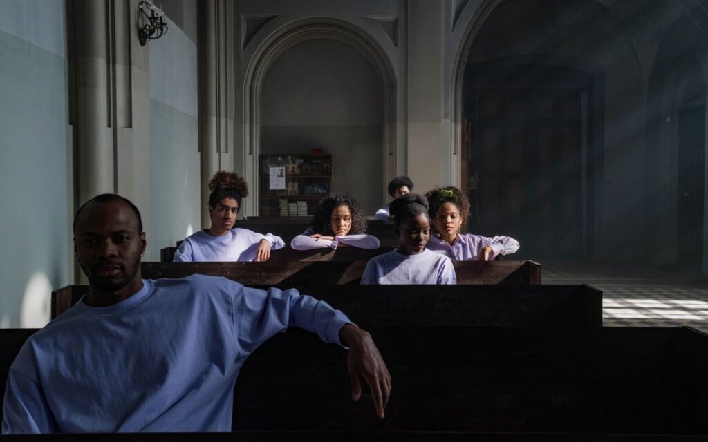 A thoughtful group sits in church pews, light streaming through the windows, creating a serene atmosphere.