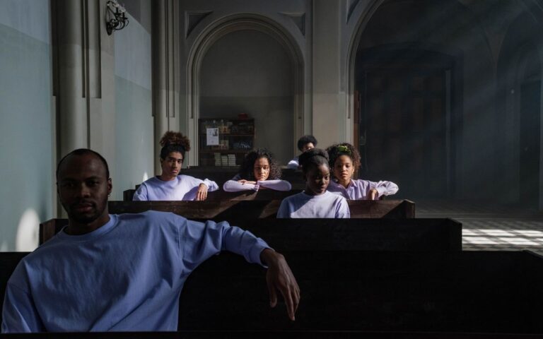 A thoughtful group sits in church pews, light streaming through the windows, creating a serene atmosphere.