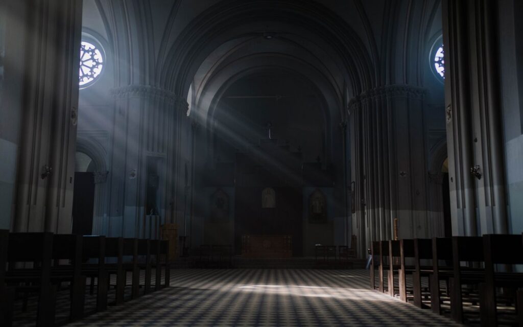 Gothic cathedral interior with sunrays illuminating the altar and arches, creating a peaceful ambiance.