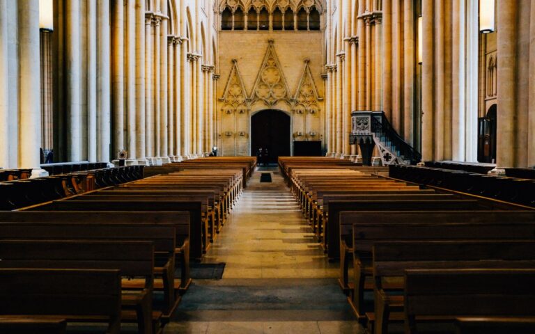 Empty pews in a Gothic cathedral interior, showcasing majestic columns and arches.