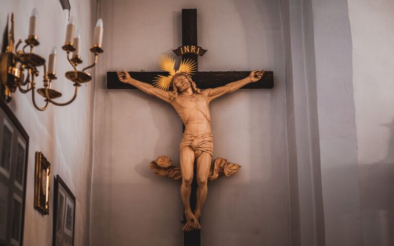 A detailed wooden crucifix sculpture inside a church showcasing religious symbolism.