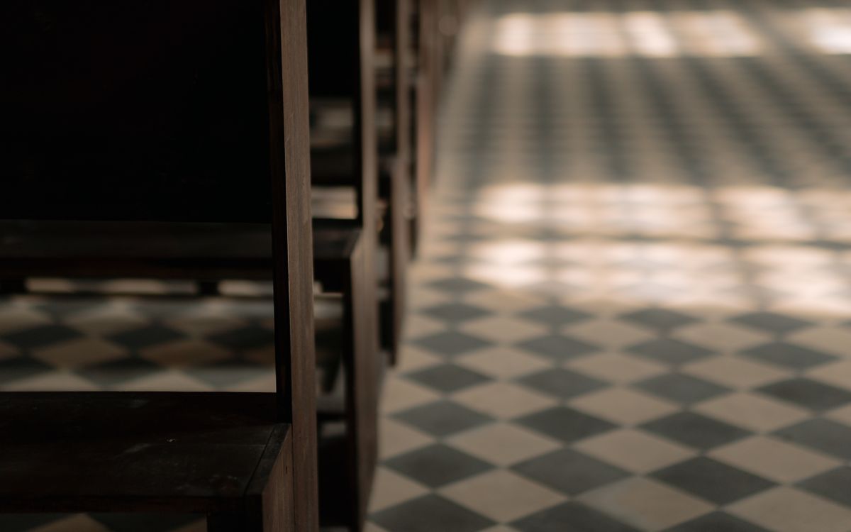 Close-up of wooden pews and checkered floor in a serene church interior.