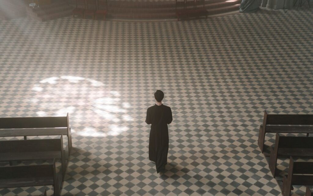 A priest walks alone inside a sunlit cathedral, exemplifying serenity and spirituality.