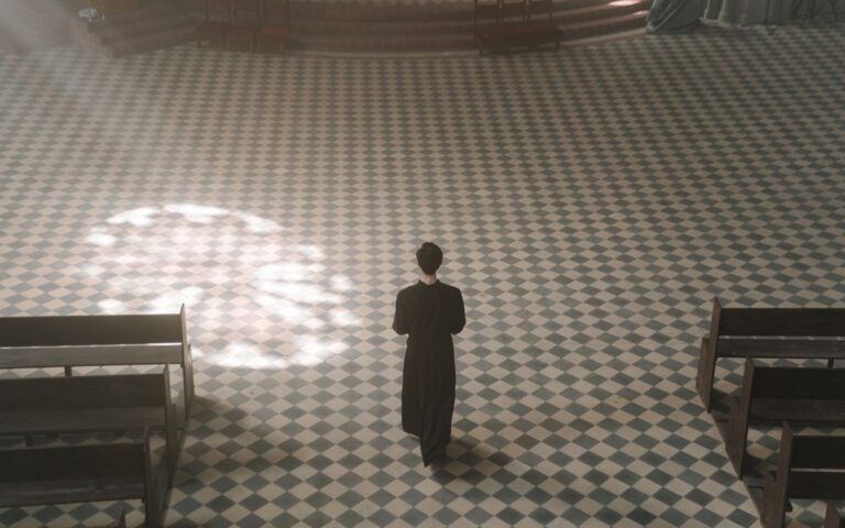 A priest walks alone inside a sunlit cathedral, exemplifying serenity and spirituality.