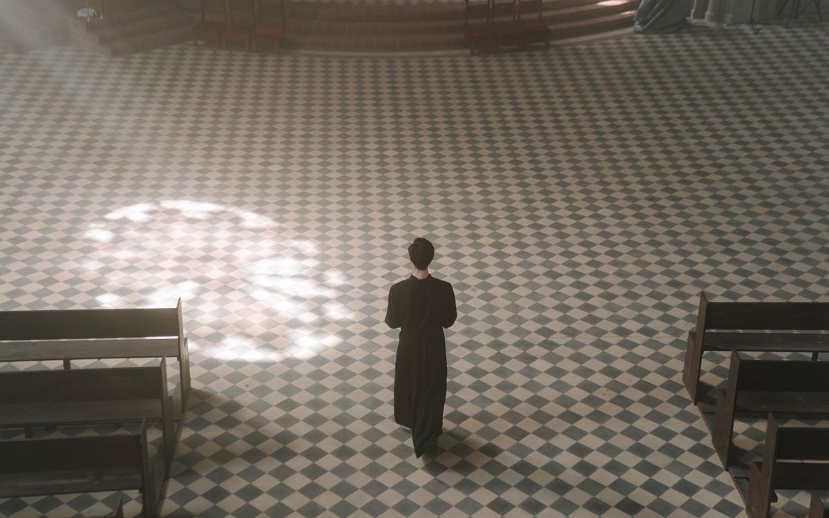 A priest walks alone inside a sunlit cathedral, exemplifying serenity and spirituality.