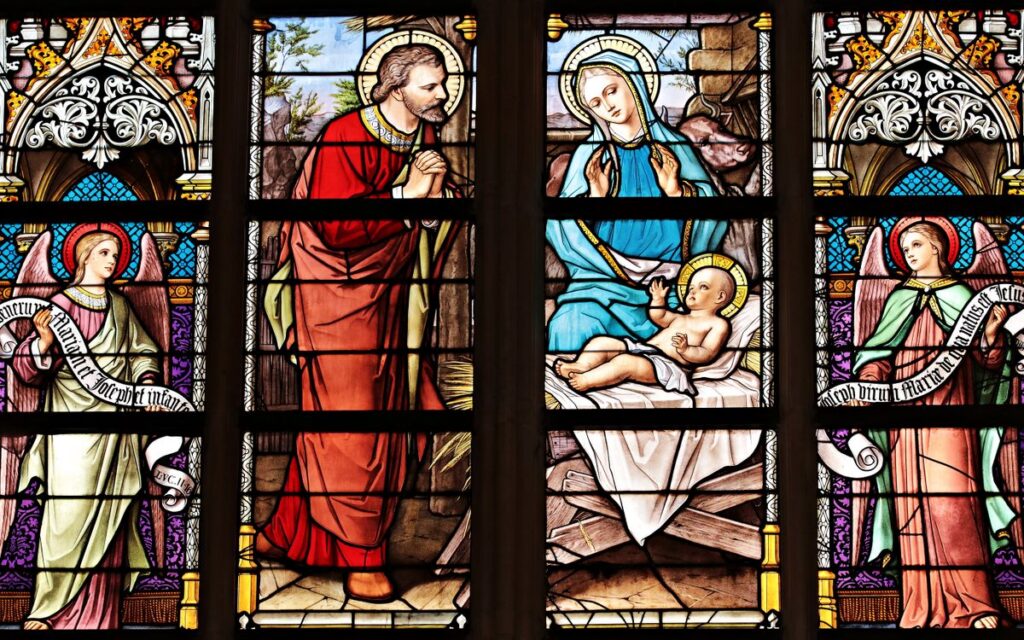 Vibrant stained glass window illustrating a biblical nativity scene with vivid colors in a church setting.