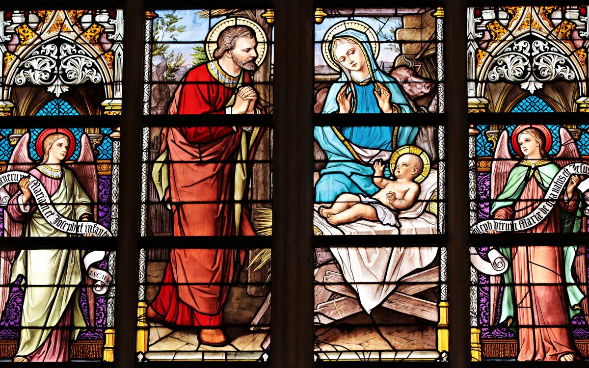 Vibrant stained glass window illustrating a biblical nativity scene with vivid colors in a church setting.