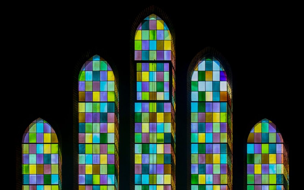 Colorful stained glass windows with gothic architecture, illuminated and vibrant.