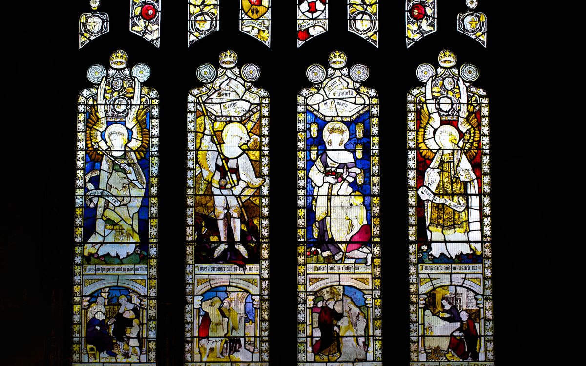Intricate stained glass windows depicting religious scenes in an English cathedral.