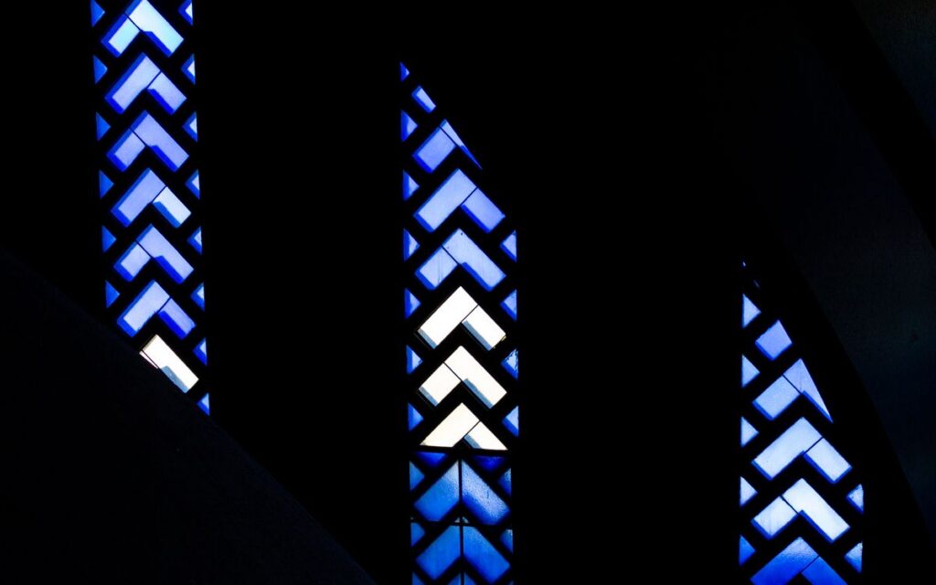 Dark abstract design featuring blue stained glass patterns with geometric shapes.