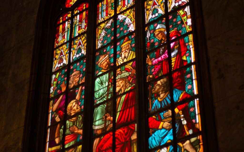 Intricate stained glass window in a cathedral depicting religious figures. Captivating colors.