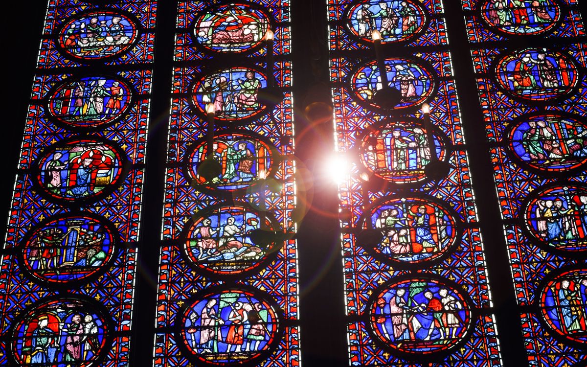 Sunlight streaming through colorful stained glass windows in a cathedral, highlighting intricate designs.