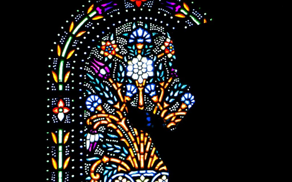 Vividly lit stained glass window depicting intricate patterns and colors.