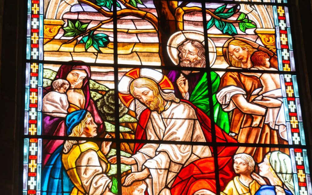 Colorful stained glass window illustrating a religious scene with vibrant characters and intricate designs.