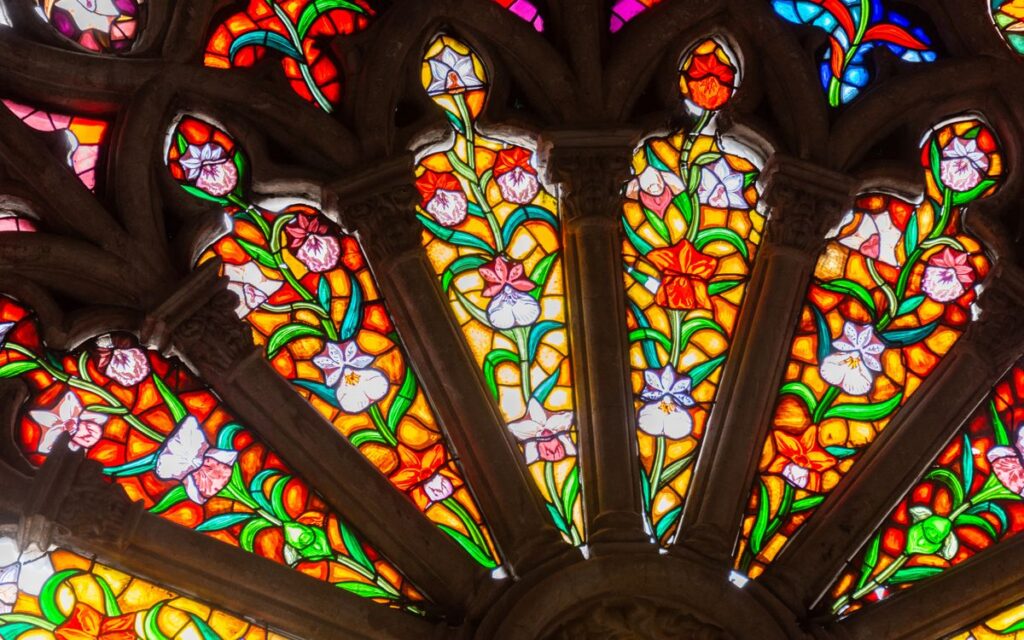 Colorful stained glass window with floral patterns in a cathedral setting.