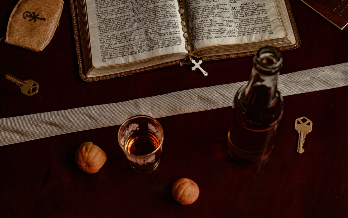 A symbolic arrangement featuring a Bible, rosary, and keys on a dark wooden table.